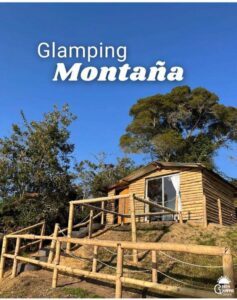 Exterior de una cabaña de madera rodeada de árboles en un entorno montañoso, ideal para un romántico retiro de glamping.