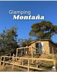 Exterior de una cabaña de madera rodeada de árboles en un entorno montañoso, ideal para un romántico retiro de glamping.