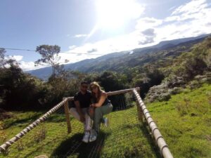 Dos personas caminando por un puente colgante en medio de un hermoso paisaje montañoso mientras disfrutan de su retiro de glamping en pareja.