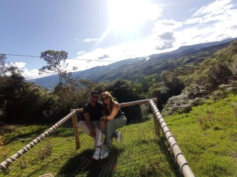 Dos personas caminando por un puente colgante en medio de un hermoso paisaje montañoso mientras disfrutan de su retiro de glamping en pareja.