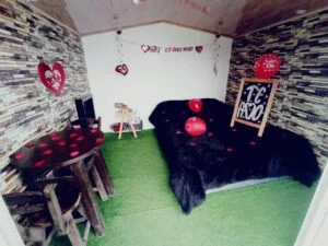 Interior de una cabaña decorada con elementos románticos como corazones, globos y un mensaje de amor, perfecta para sorprender a tu pareja durante el glamping.